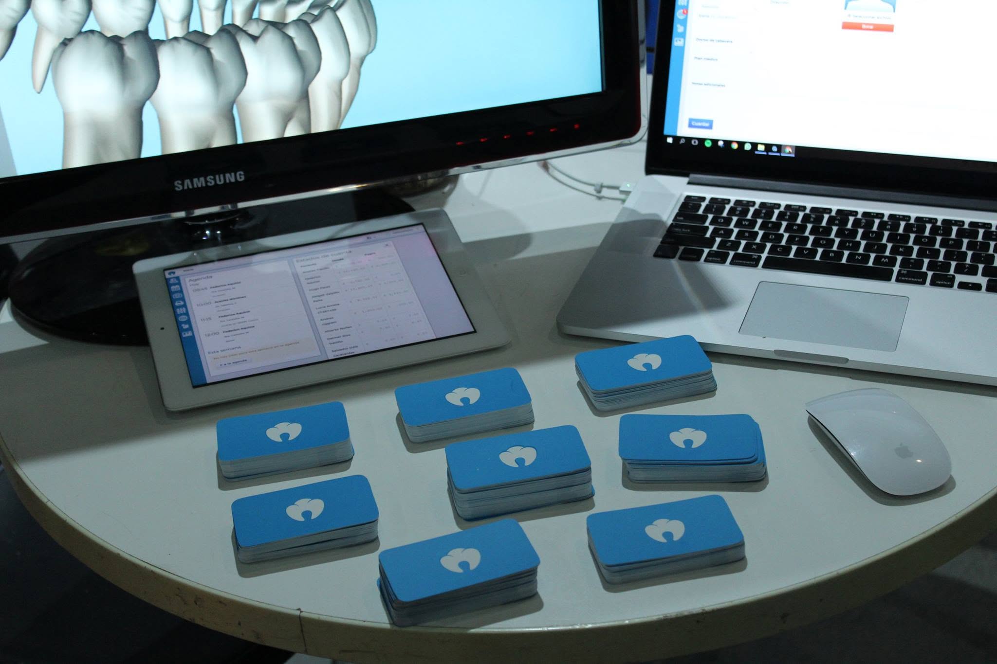 Mesa con el odontograma en pantalla, una tablet y tarjetas de Hessy